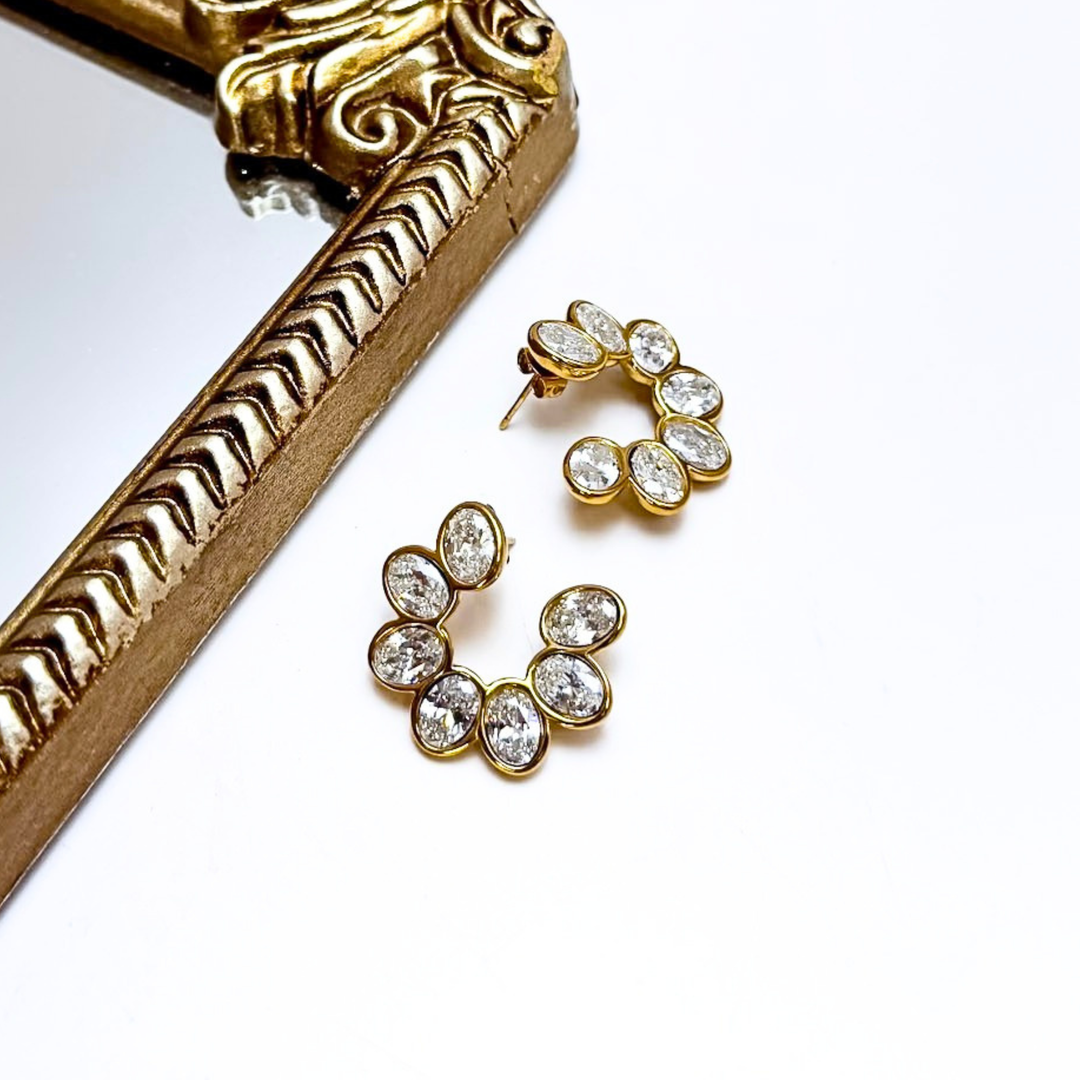 Gold earrings with clear stones on a white background