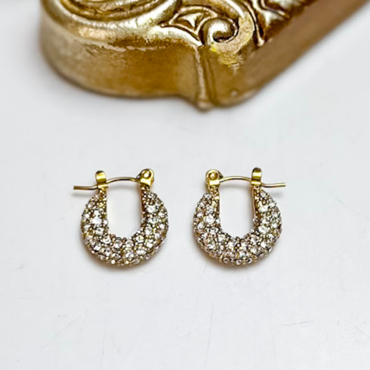 Chan Sutt Pearls Ava Pavé Huggie Hoop Earrings in Gold featuring petite gold-tone huggie hoops with sparkling pavé-set clear crystals and a hinged closure.
