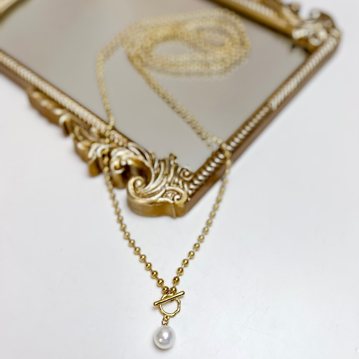  Necklace featuring a delicate gold-tone beaded chain, toggle-style accent, and single white pearl drop pendant.