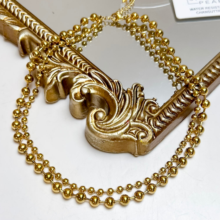 CHANSUTT PEARLS XL Beaded Necklace in Gold featuring layered strands of polished gold-tone round beads in varying sizes.