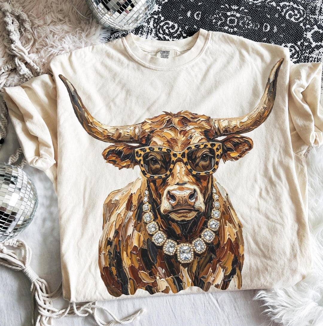 Natural graphic tee featuring a fashionable longhorn wearing leopard-print sunglasses and a crystal statement necklace.