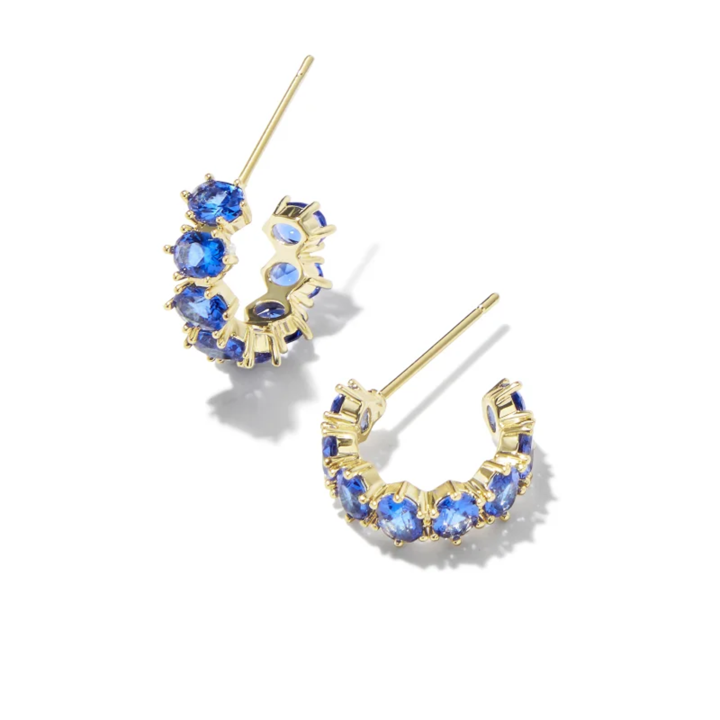 These Cailin Gold Crystal Huggie earrings in Blue Crystal by Kendra Scott are pictured on a white background.