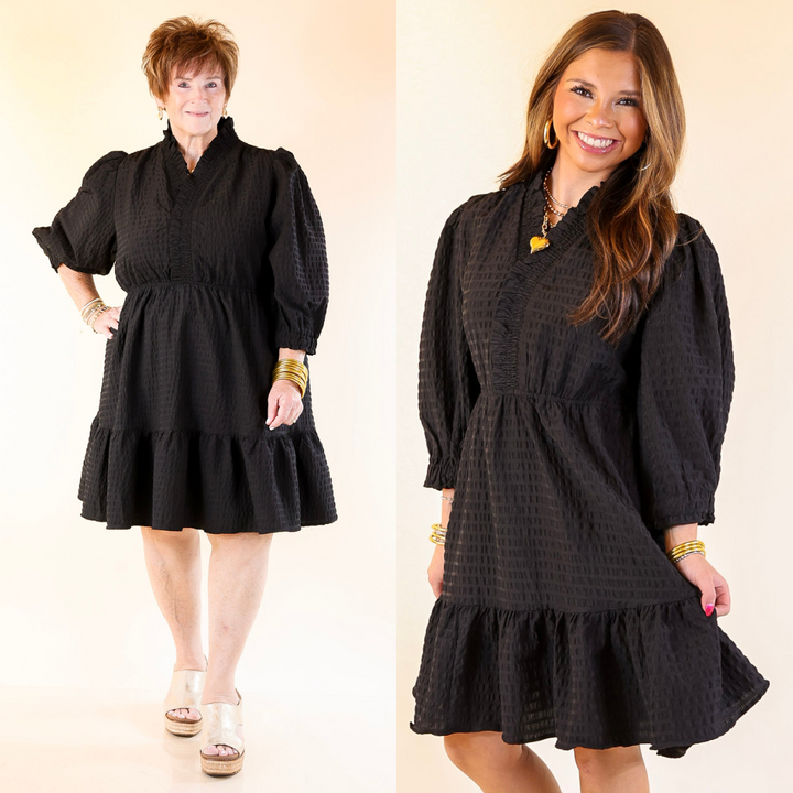 Two women wearing black dresses on a plain background