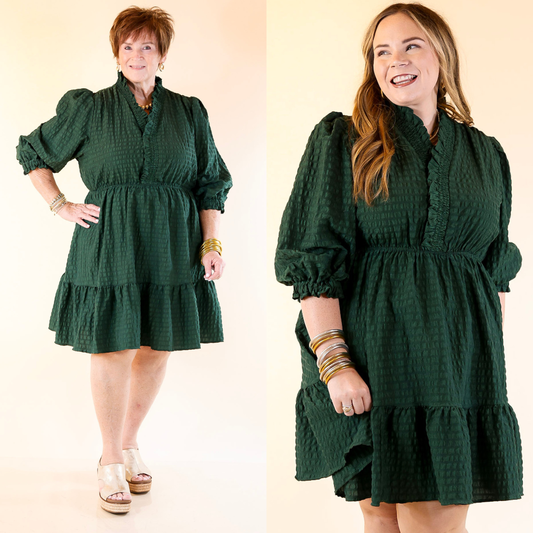 Two women wearing emerald green dresses against a plain background