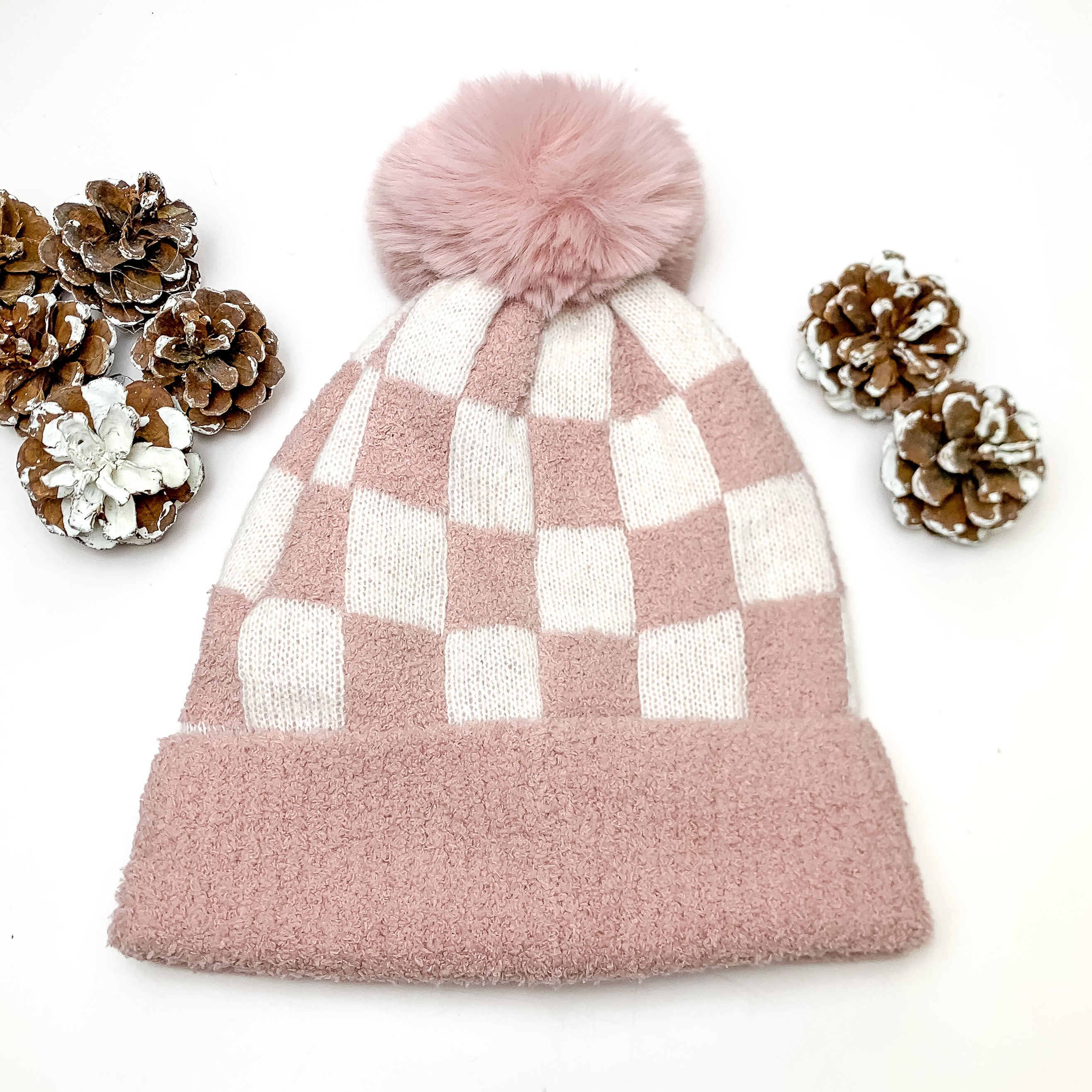 Checkered Beanie in Light Pink and White. This beanie is pictured on a white background with pinecones around it.