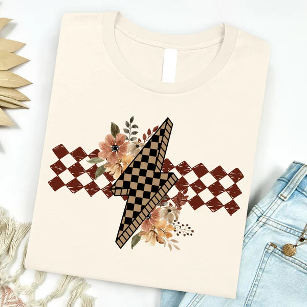 Beige t-shirt with a decorative design featuring flowers and checkered patterns on a white background.