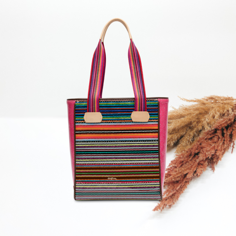 Colorful striped tote bag with a white background and dried grasses.