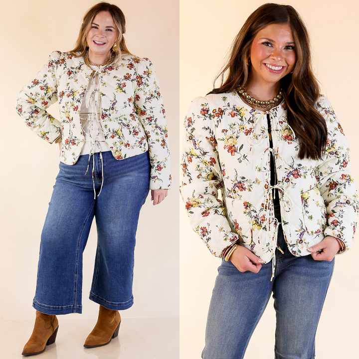 Two women wearing floral jackets with bow tie detailing and blue jeans on a beige background