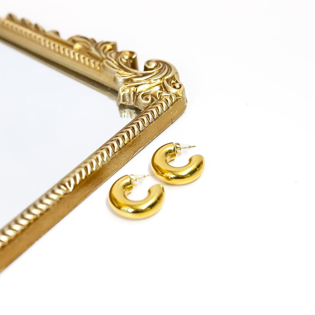 Gold earrings and decorative gold bar on a white background