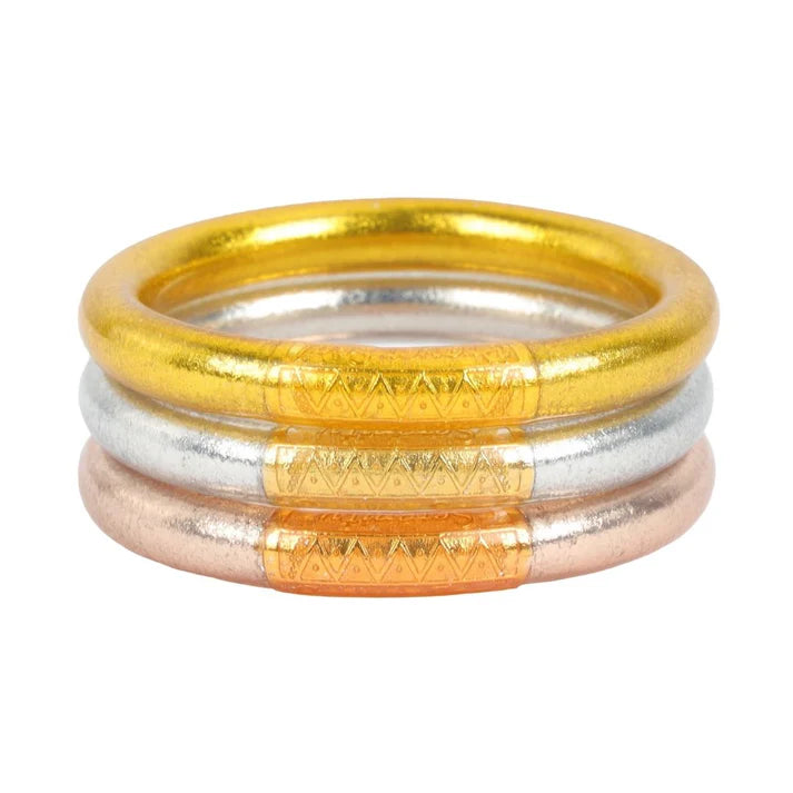 A stack of 3 tube bracelets (top to bottom) gold, silver, and champagne. 