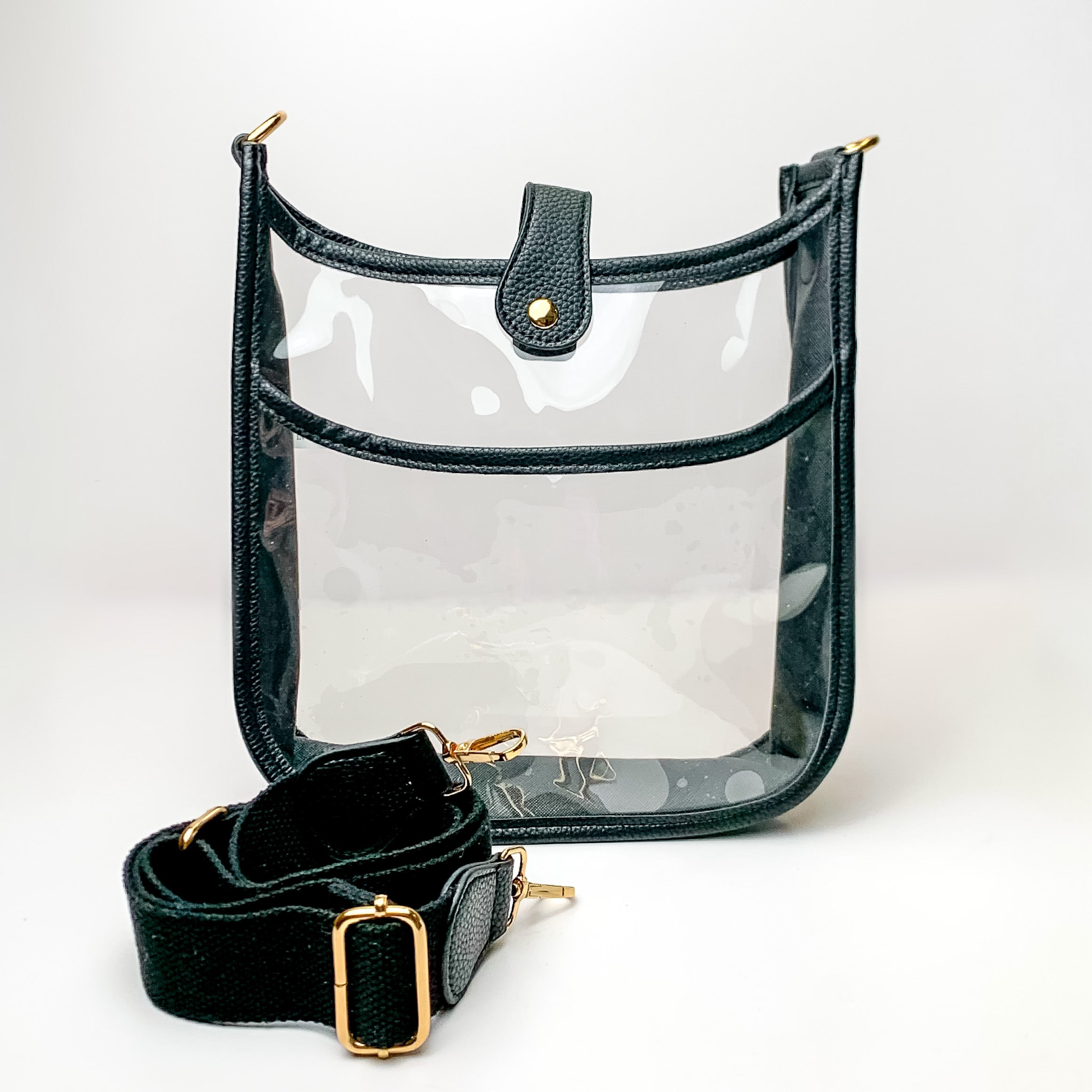 Clear crossbody purse in black with a black purse strap pictured in front of the purse. This purse is pictured on a white background. 