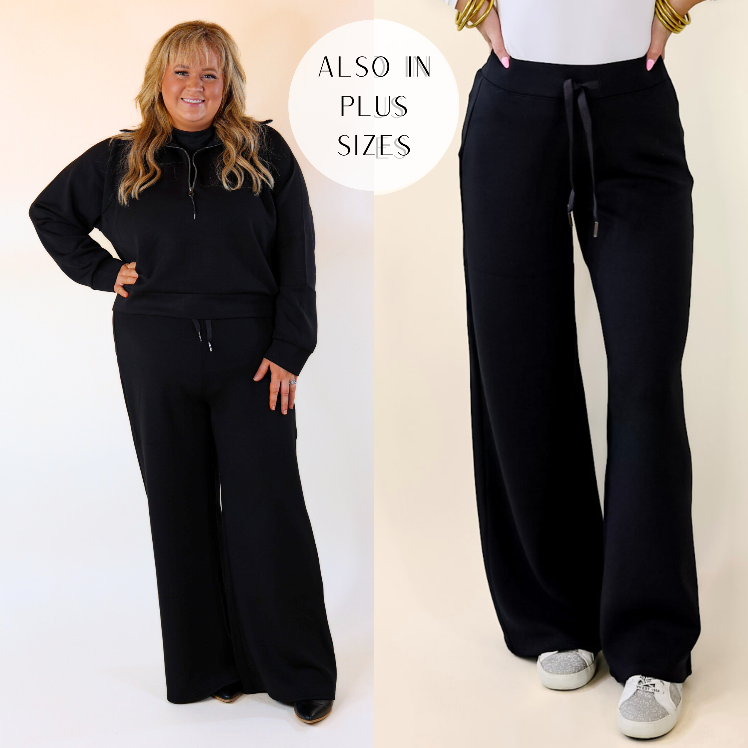 Model is wearing a pair of wide leg sweatpants in black. Model has these pants paired with silver sneakers, a white bodysuit, and gold jewelry.