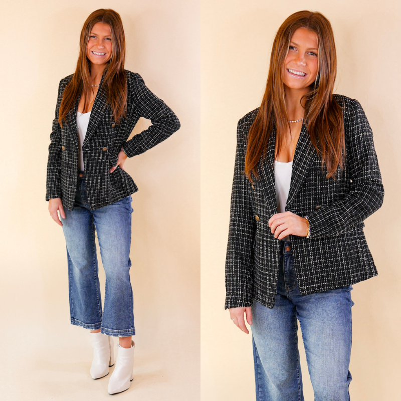 Model is wearing a black tweed blazer with bronze buttons. Model has paired the blazer with a white bodysuit, cropped blue jeans, white booties, and gold tone jewelry. 