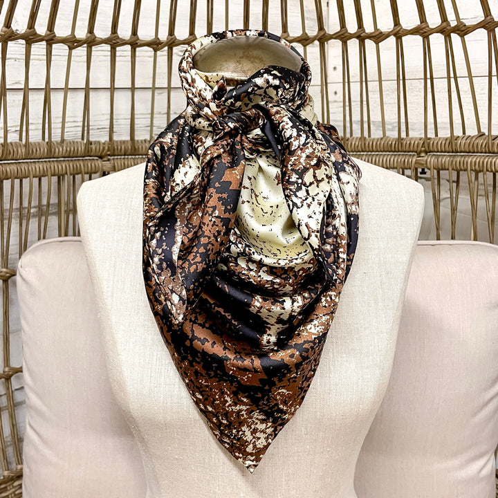 Mannequin wearing a patterned scarf with a candle on a wicker chair