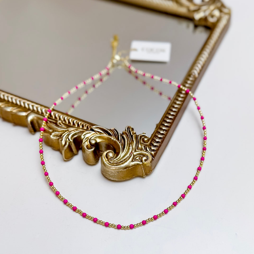 Necklace with pink beads on a decorative gold frame