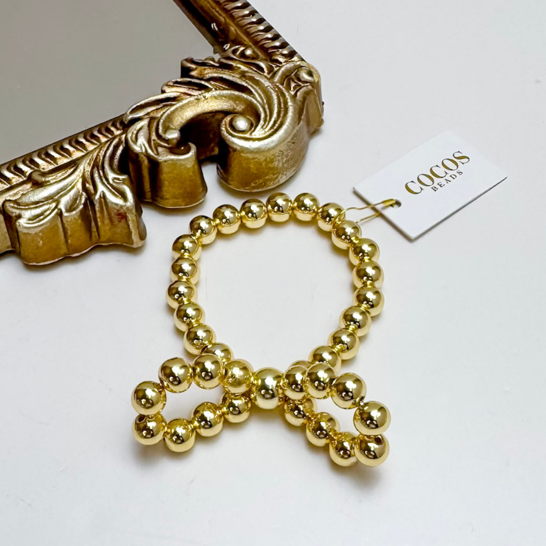 Gold beaded bow-shaped earring with decorative gold frame and &