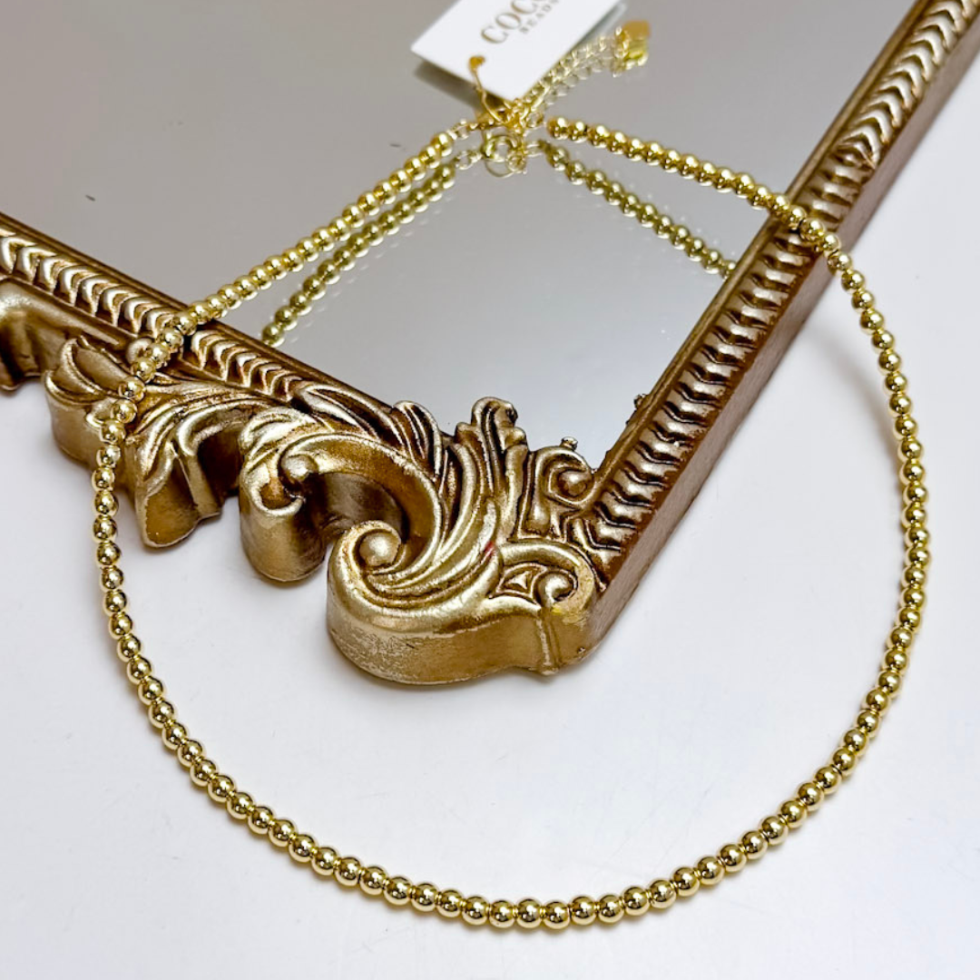 Decorative gold frame with intricate designs and a chain on a white background