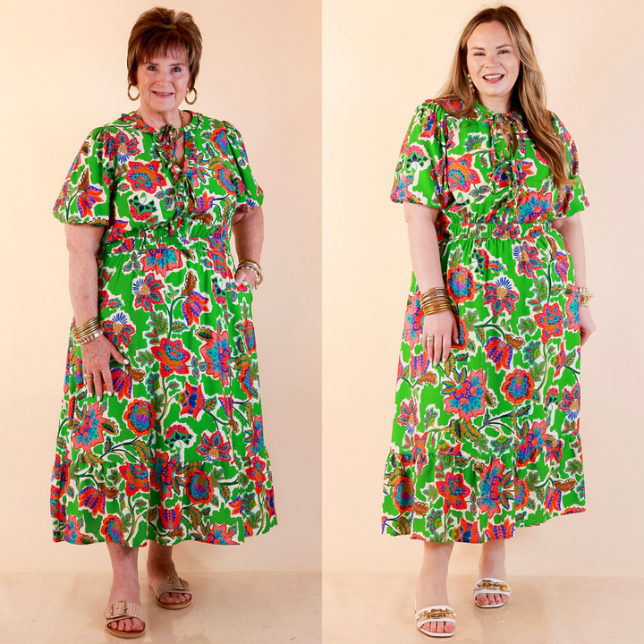 Models are wearing Floral Print Midi Dress with Tie Neckline and Puff Sleeves in Green against a beige backdrop. 