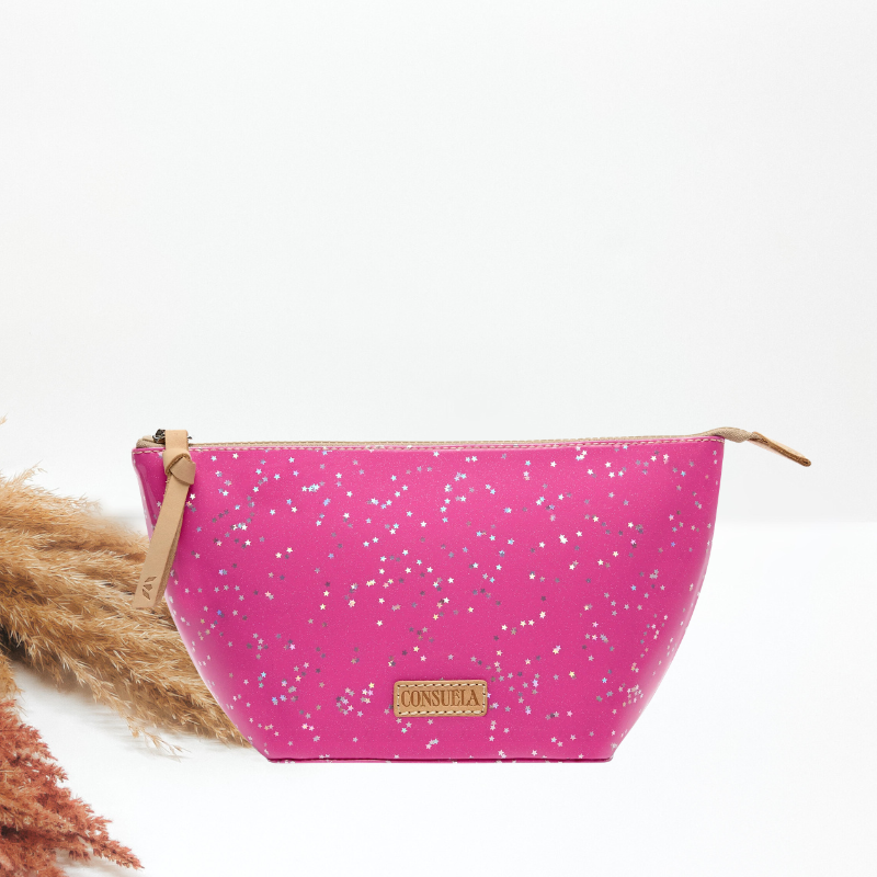 A pink glitter-speckled cosmetic bag with a tan leather zipper pull and wrist strap, and a Consuela leather brand plate.