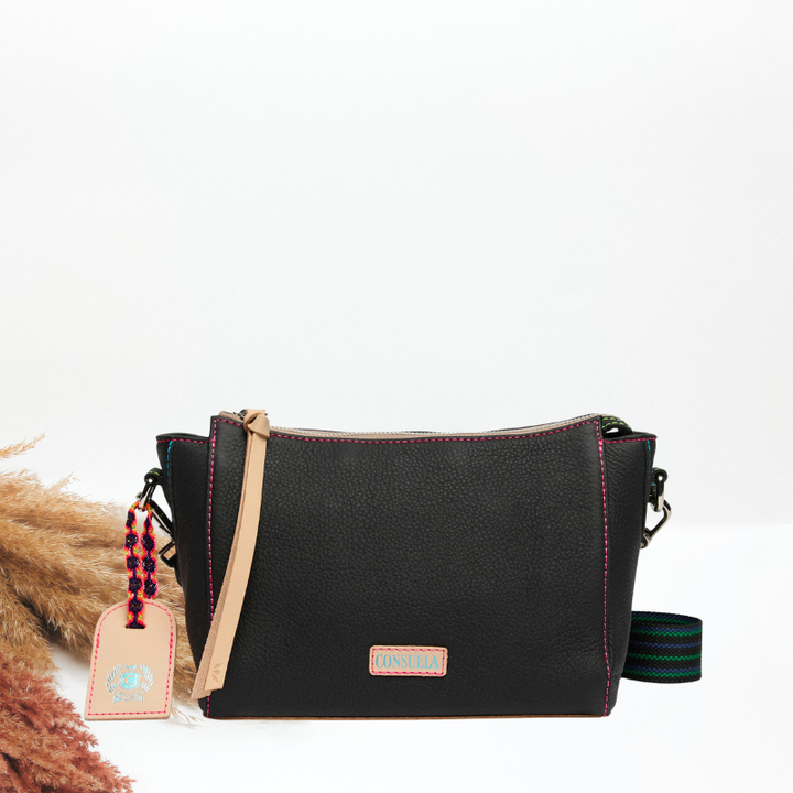 Black handbag with a strap and decorative tag on a white background