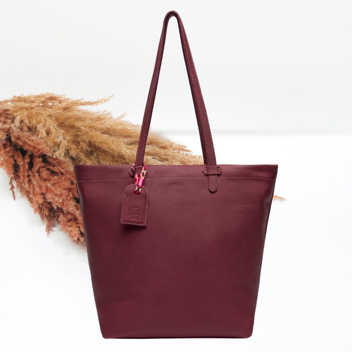Maroon tote bag with a visible brand tag on a white background