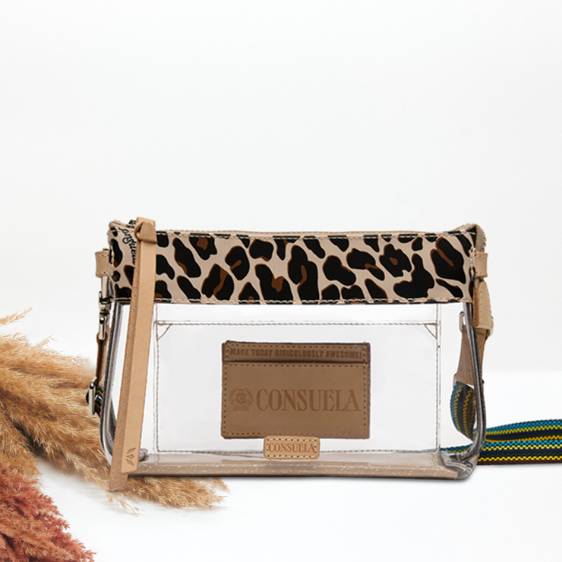 A clear plastic crossbody bag with a leopard print top flap, tan leather trim, and a tan brand patch reading &