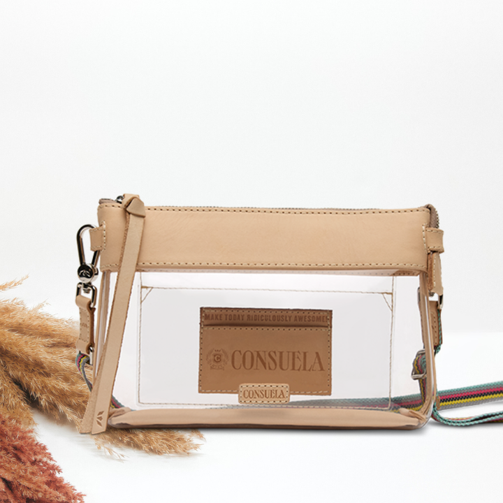 A clear plastic crossbody pouch bag with beige faux-leather trim and strap, featuring a brown leather brand patch that reads &