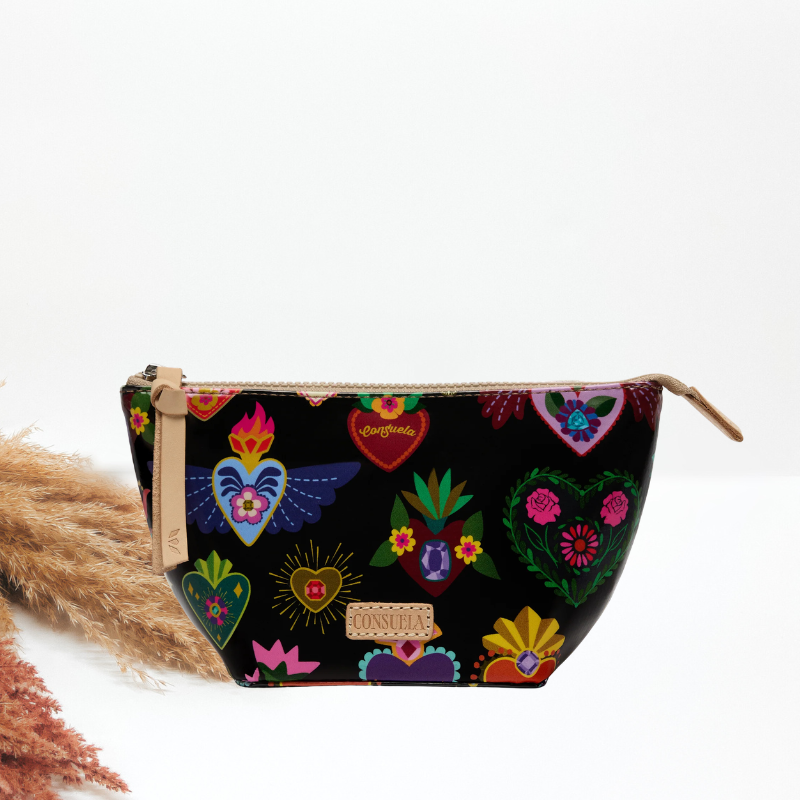 A black zippered cosmetic pouch featuring a colorful Mexican Day of the Dead (Día de los Muertos) print with sugar skulls, hearts, and flowers, shown on a white background with dried pampas grass.