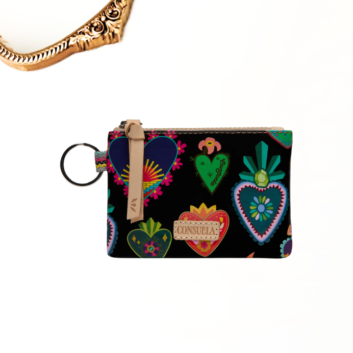 A small zip pouch with a black background and colorful heart motifs, featuring a tan wrist strap and a black key ring. A partial gold ornate bracelet is visible at the top left on a white background.