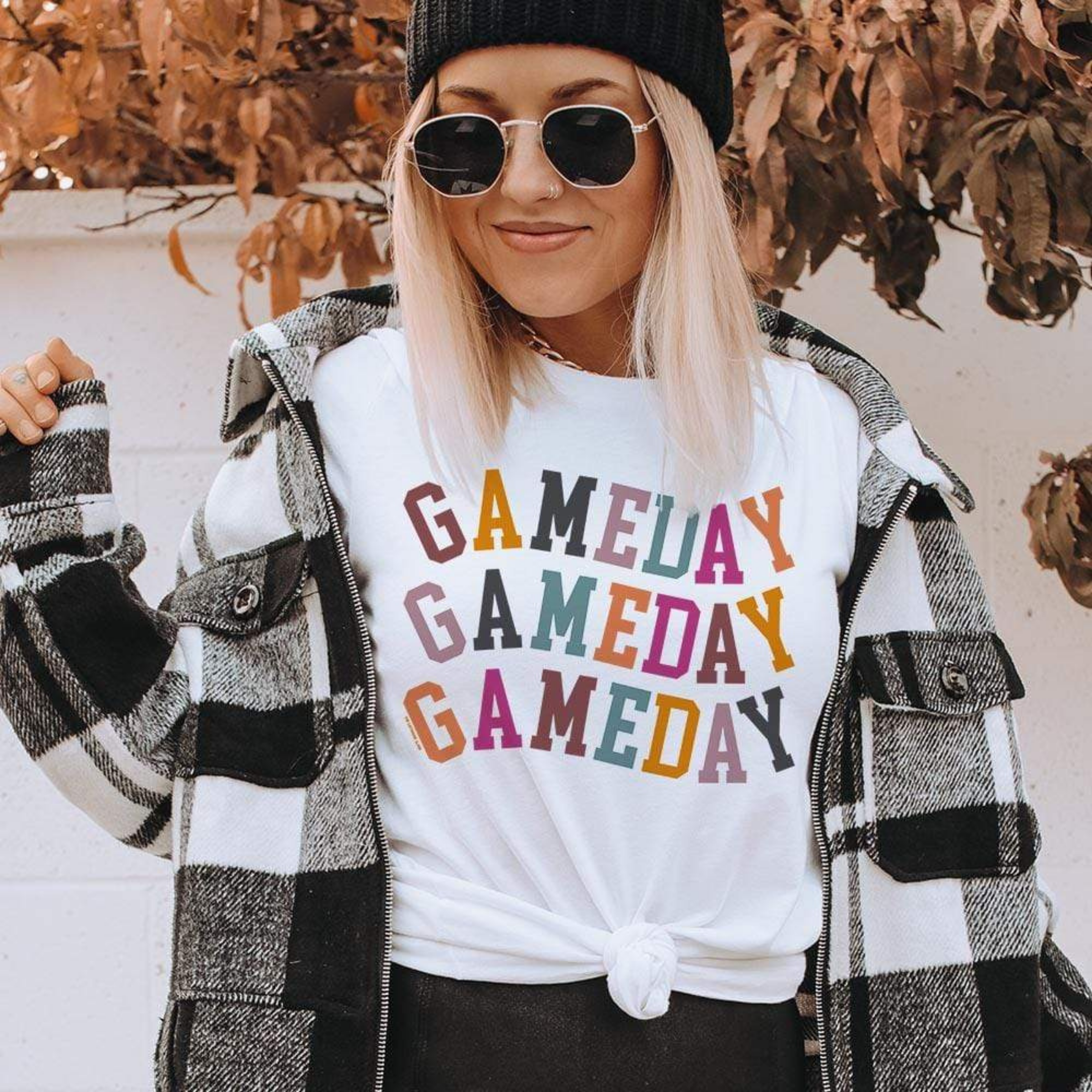 Model is wearing a white short sleeve crewneck tee featuring a multicolor graphic of the words "Gameday"