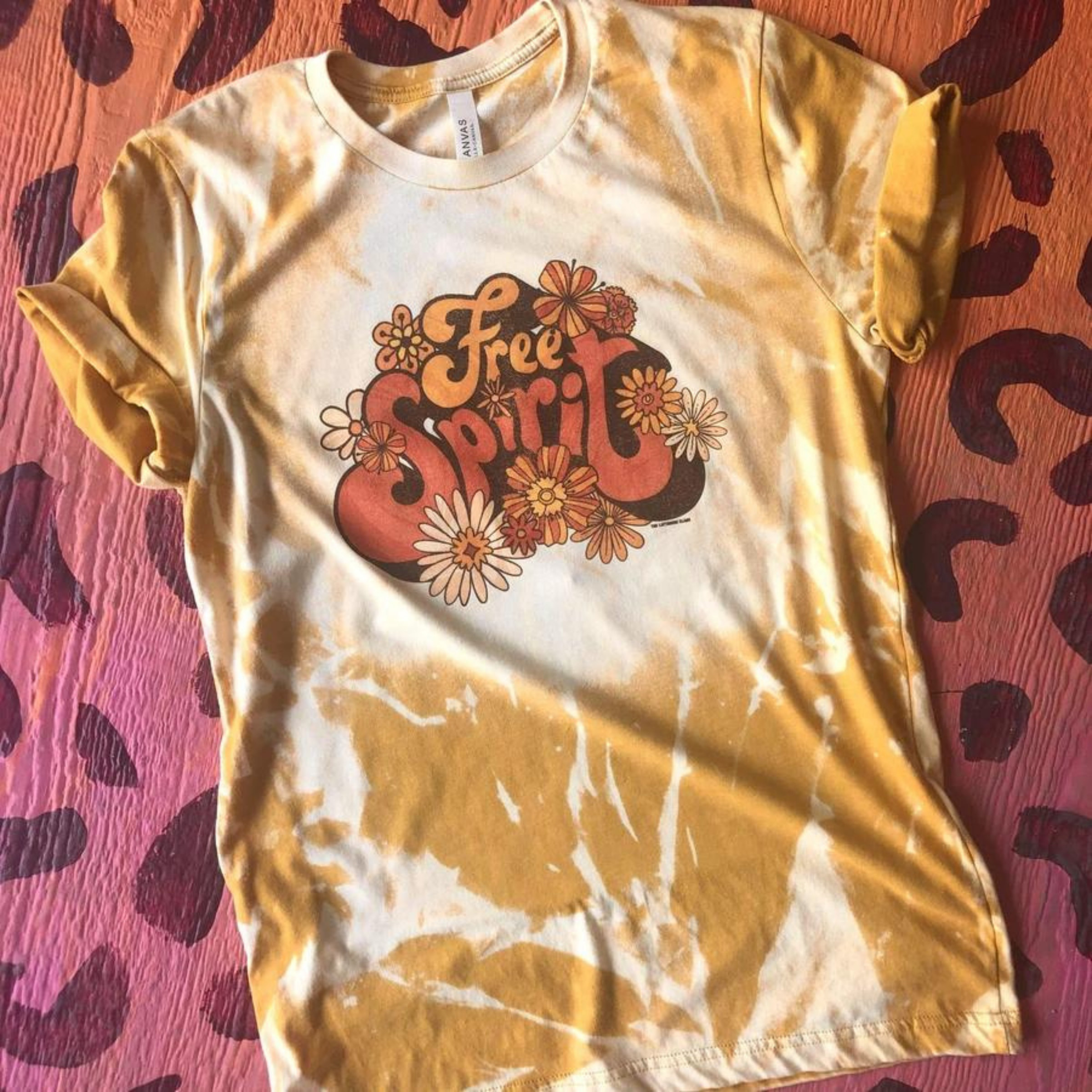 Yellow and white tie dye crew neck tee shirt that says "Free Spirit" in bubble letters and has flowers around it.