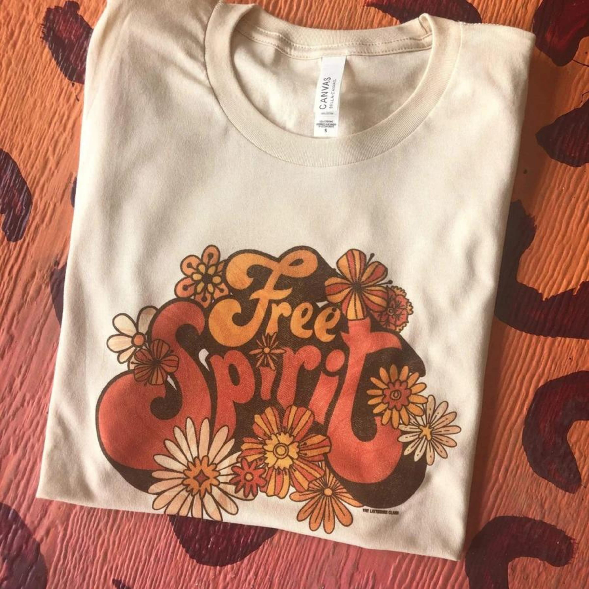 Ivory crew neck tee shirt that says "Free Spirit" in bubble letters and has flowers around it.