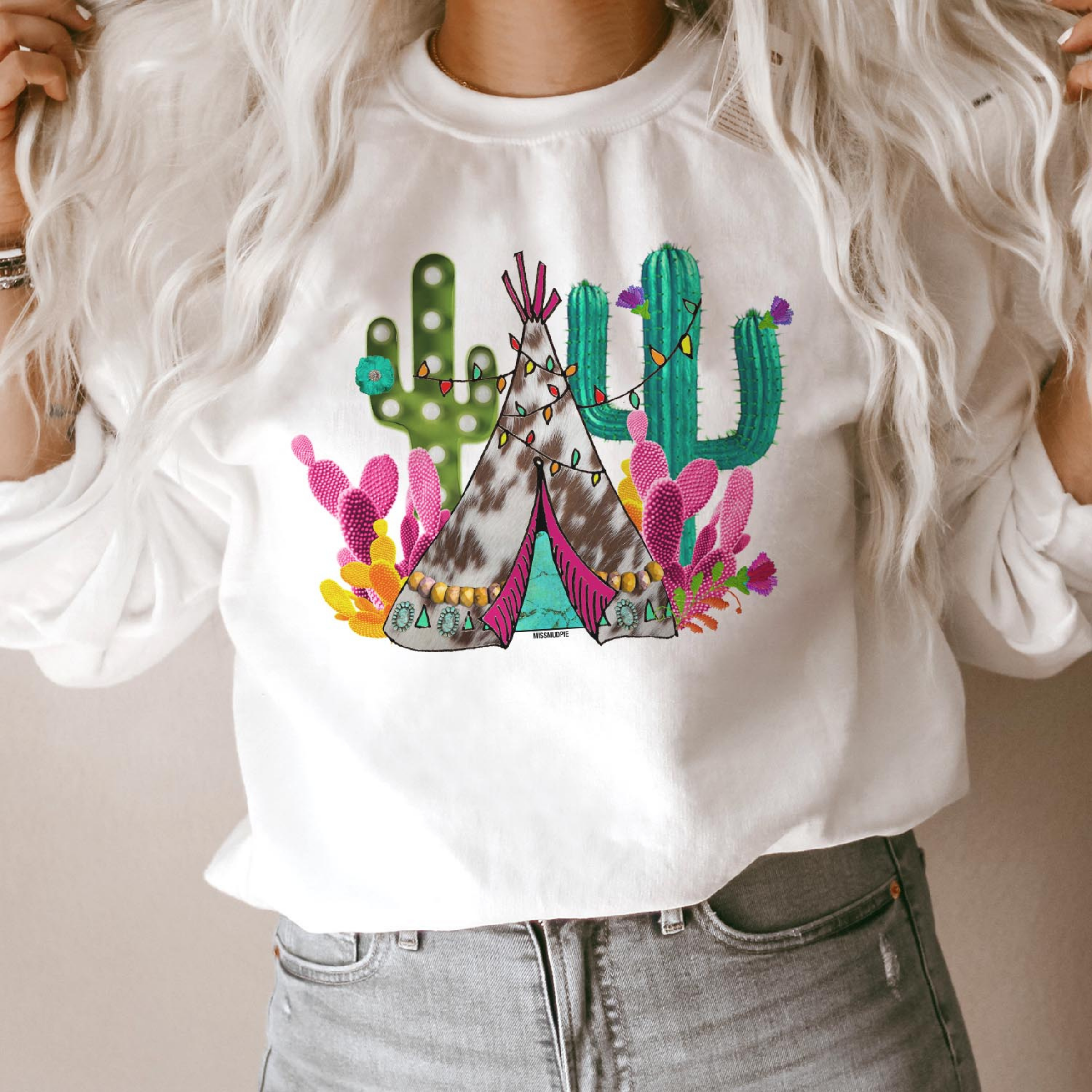 This white pullover includes a crew neckline, long sleeves, and a teepee and cactus Christmas graphic in fun, bright colors. This is modeled here with rolled sleeves and a pair of light wash denim jeans. 
