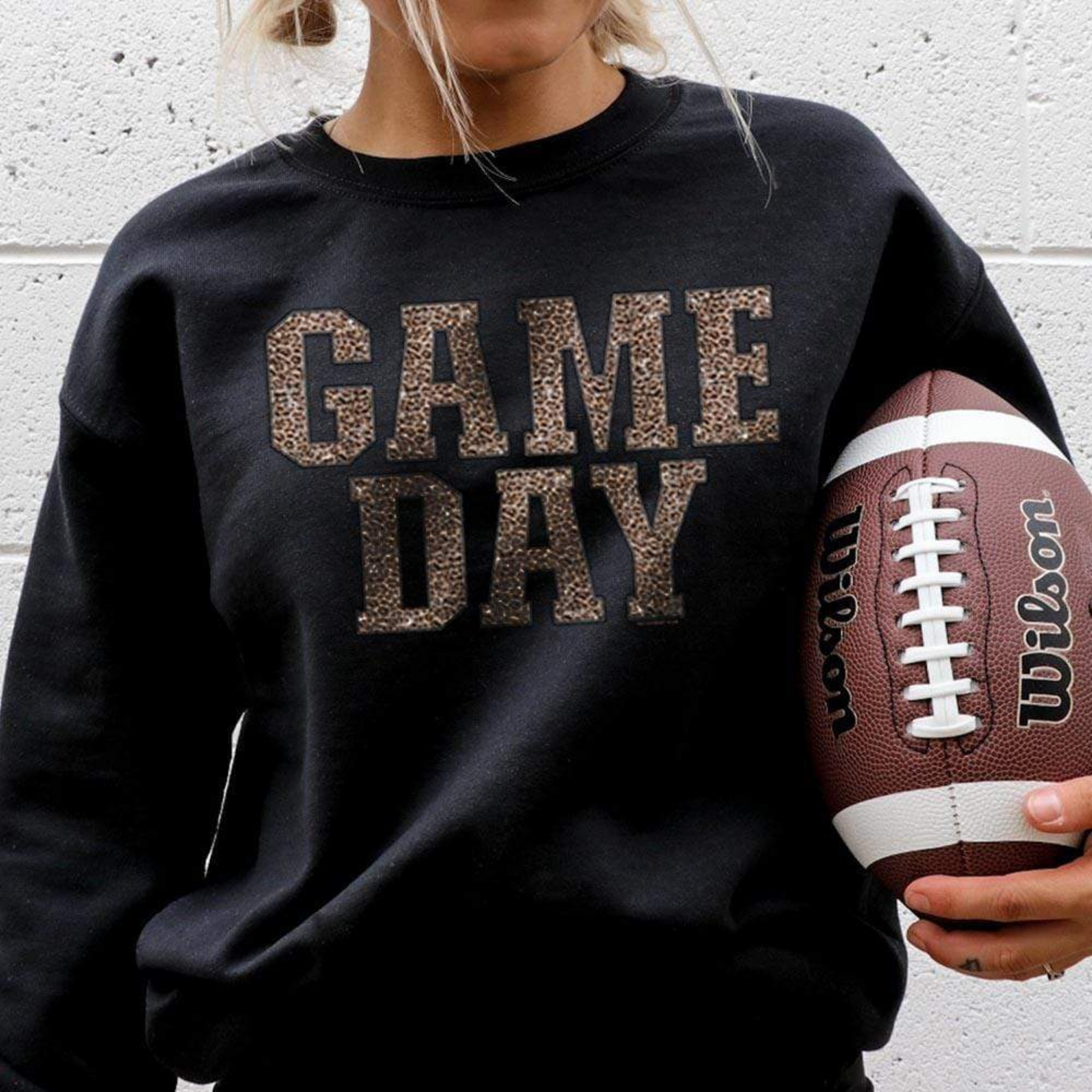 Model is wearing a black sweatshirt featuring a leopard print graphic that says "Game day"