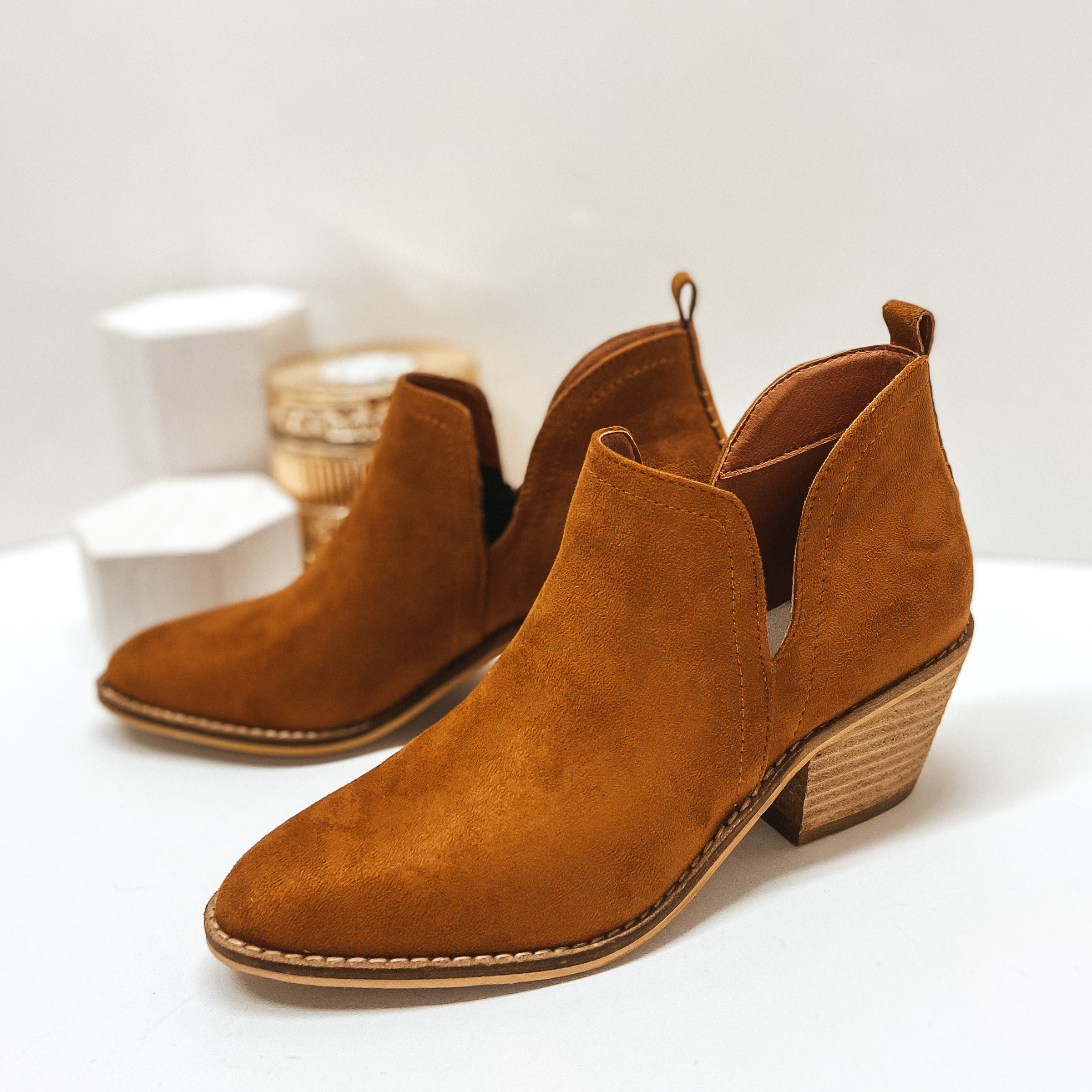 Brown booties with ankle skits and heel tab. Pictured on white background.