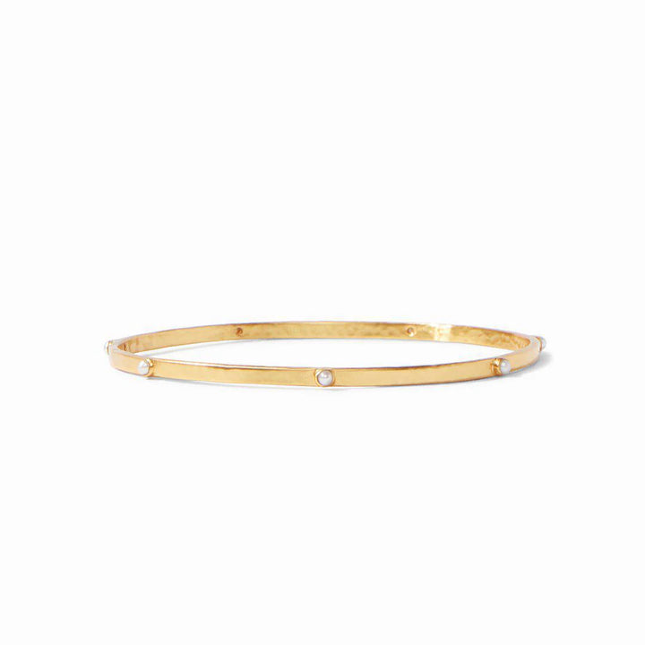 A gold bangle bracelet with pearl accents on a white background.