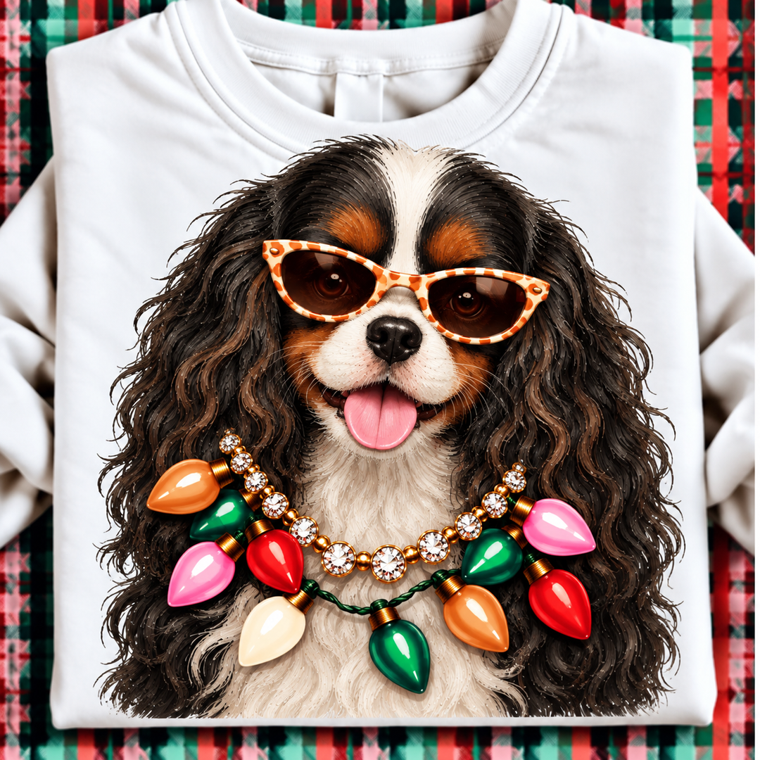 Holiday Boujee Black and Tan Cavalier King Charles Christmas graphic tee or sweatshirt featuring a black, tan and white Cavalier King Charles Spaniel in statement sunglasses with a crystal necklace and Christmas lights on white
