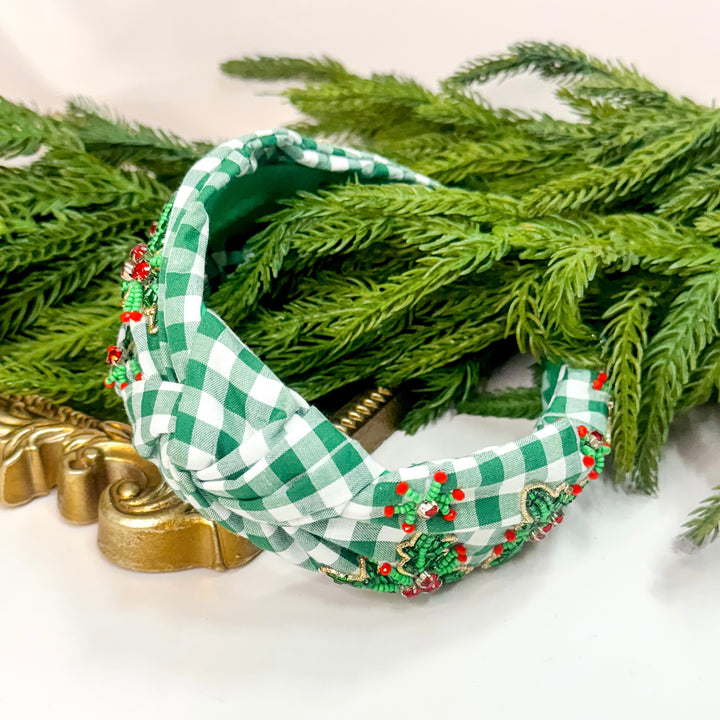 Green and white checkered headband with red embellishments on a white background with greenery.