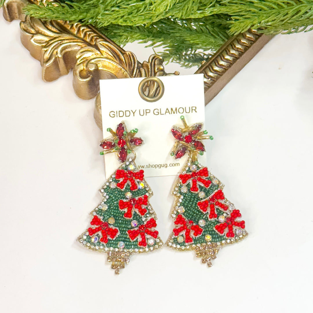 Christmas tree-shaped earrings with red bows on a 'Giddy Up Glamour' card.