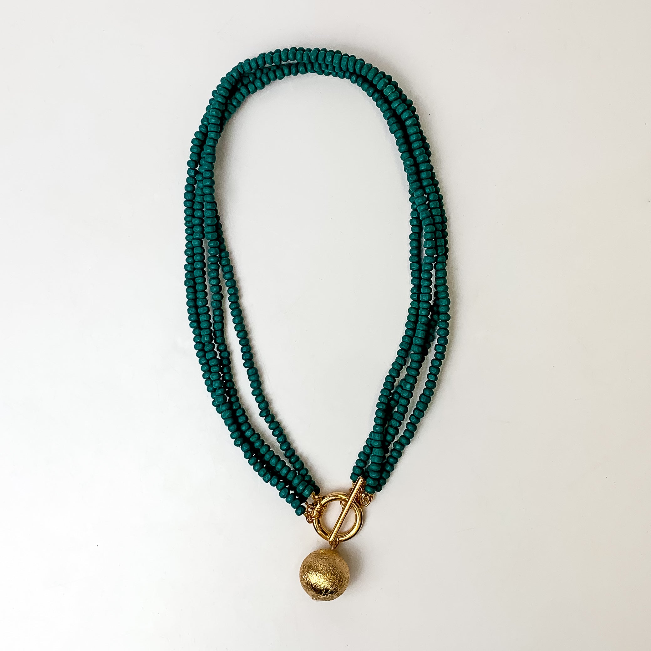 This beaded necklace has 4 strands and features a gold tone ball as the centerpiece. It is taken on a white background.
