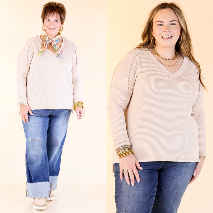Two women wearing beige tops and blue jeans against a plain background