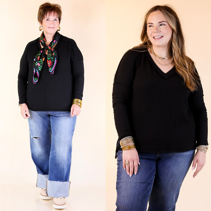 Two women wearing black tops and blue jeans against a beige background