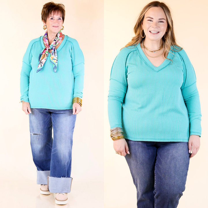 Two women wearing turquoise sweaters and blue jeans on a beige background