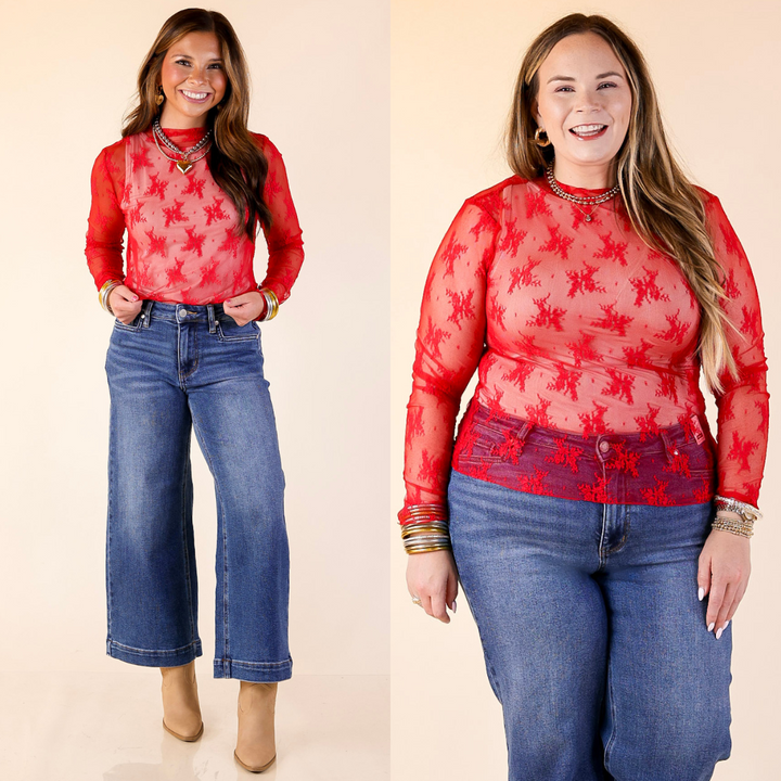 Two women wearing red lace top and blue jeans on a beige background
