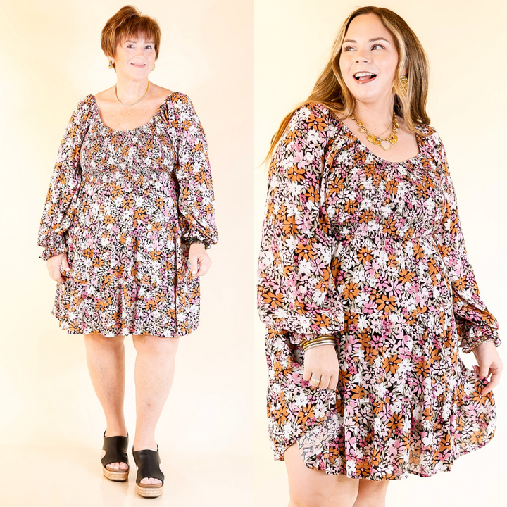 Two women wearing light pink and rust floral dresses against a beige background.