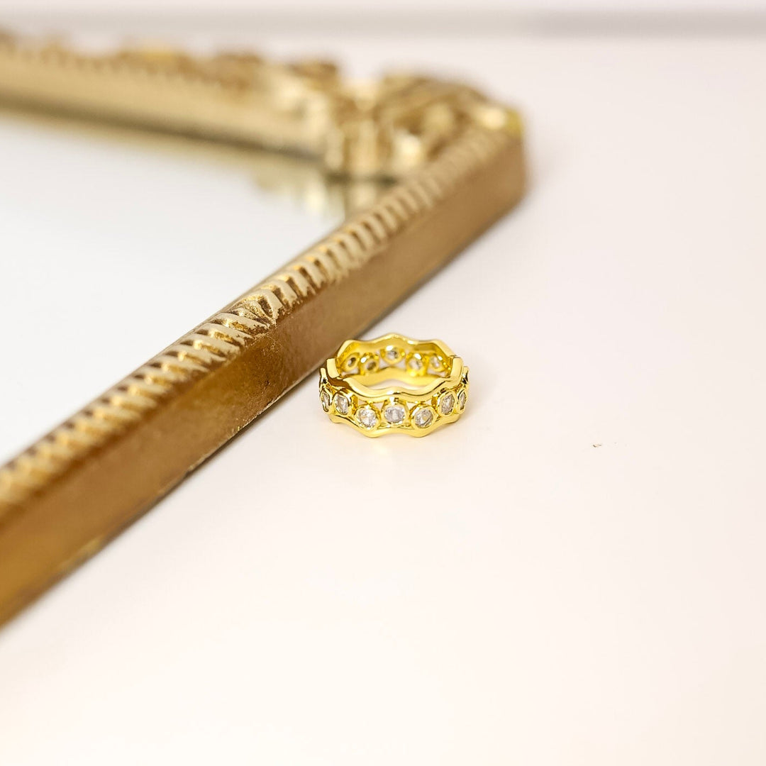 Gold ring on a white background with a gold decorative mirror