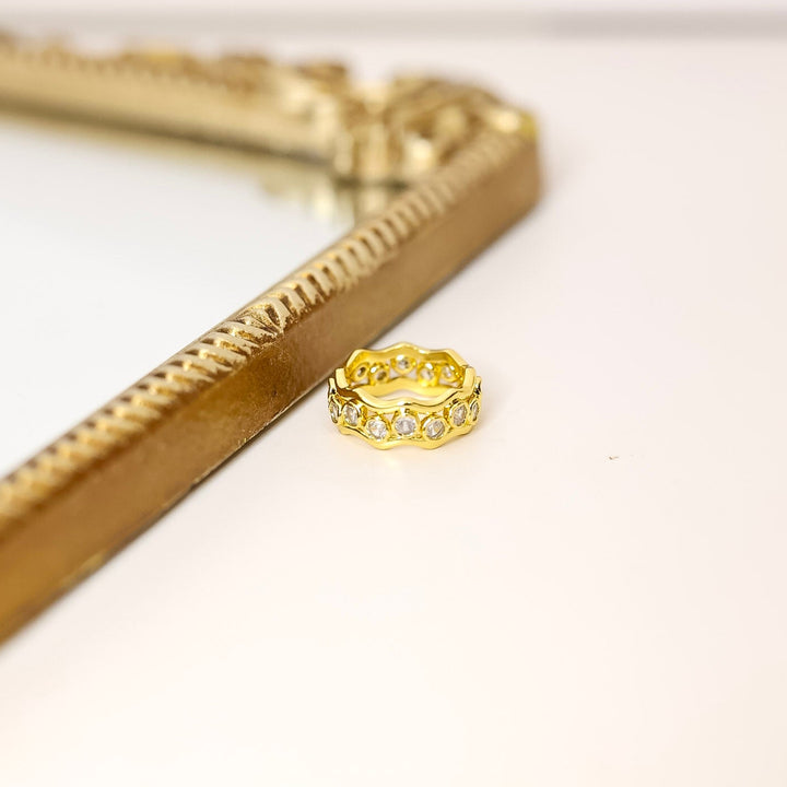 Gold ring on a white background with a gold decorative mirror