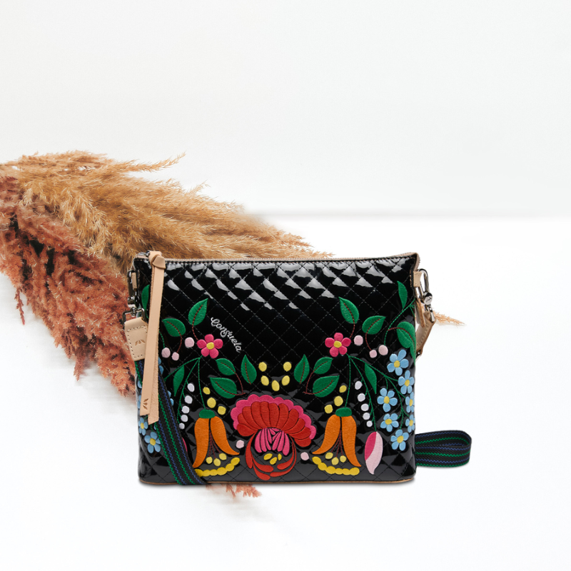 Black quilted handbag with colorful floral embroidery on a white background