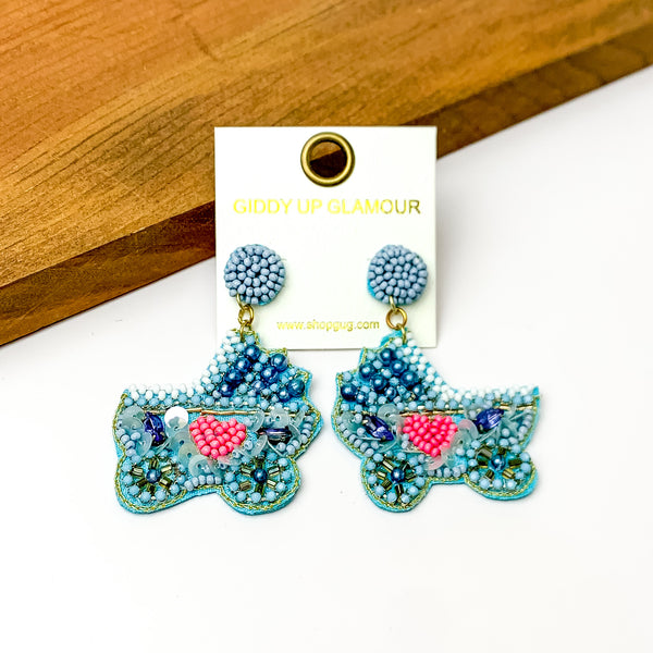 Beaded Stroller Drop Earrings with Pearls and Crystals in Blue Mix. Pictured on a white background with a wood piece in the back.