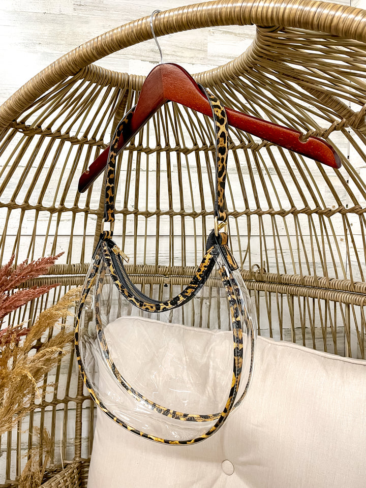 Hanging handbag with a patterned strap against a wicker chair background